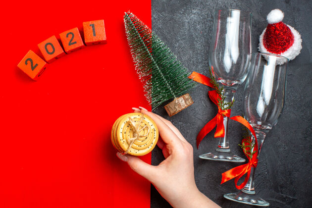 视图手捧饼干的俯视图圣诞树数字红色和黑色背景上的圣诞老人帽子圣诞新年圣诞老人