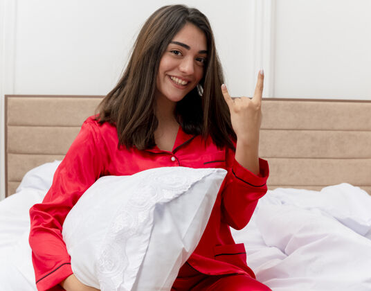 床穿着红色睡衣在床上放松的年轻美女符号表演女人