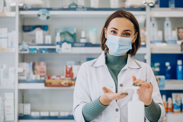 药物年轻的女药剂师用消毒剂洗手化学家面具诊所