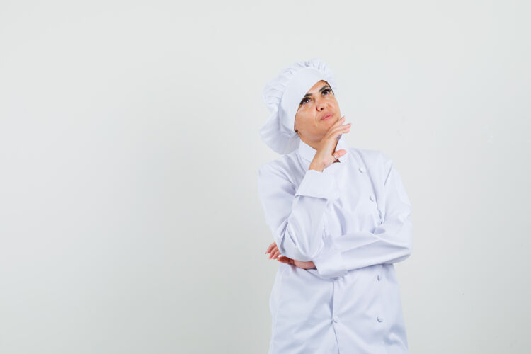 专业身着白色制服的女厨师抬起头来 神情沉思服务帽子烹饪