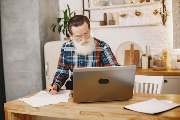 无线拿着笔记本电脑的老人坐在圣诞装饰品里的爷爷穿手机衫的男人笔记本电脑男性房子