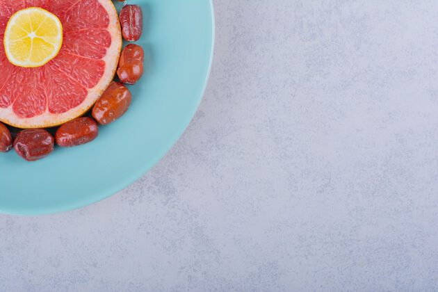 食物把成熟的葡萄柚 柠檬和银莓片放在蓝色盘子里葡萄柚有机水果