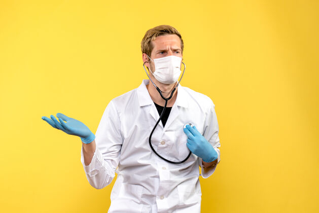 诊所正面图黄色背景上戴口罩的男医生健康大流行病毒男性大流行医务人员
