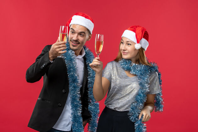 成人正面图年轻夫妇在红色地板上庆祝新年爱圣诞节颜色美丽帽子