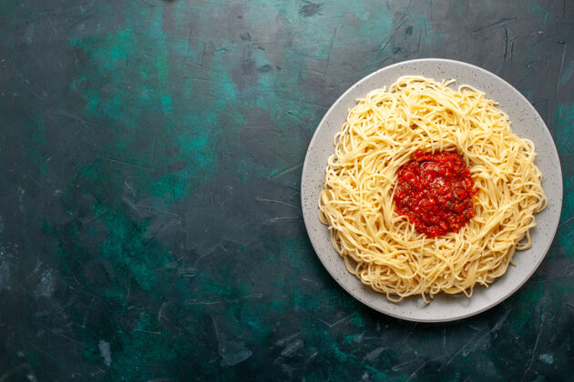 烹饪在深蓝色的桌子上俯瞰着意大利面和肉末和番茄酱奶酪比萨饼生的