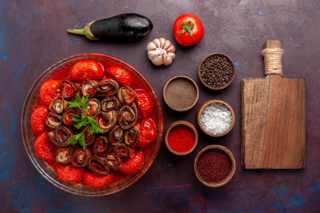 一餐顶视图熟蔬菜餐番茄和茄子与调味品在黑暗的表面晚餐水果西红柿