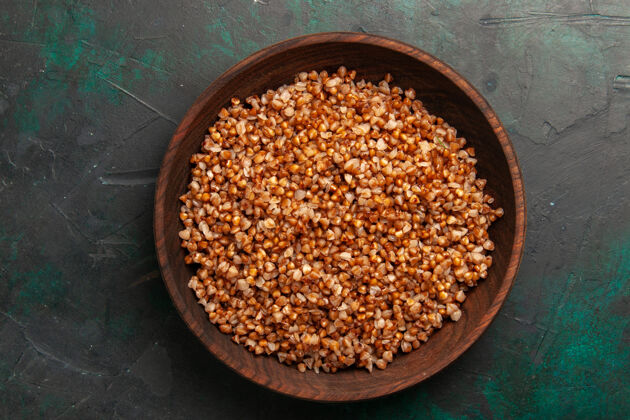 配料顶视图熟荞麦美味的饭菜内棕色盘子在深绿色的表面烹饪农产品顶部
