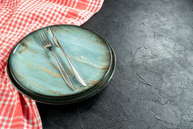 晚餐底视钢叉和餐刀放在圆盘子上红白格子桌布放在黑桌子上自由空间方格观点刀