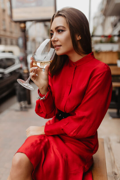 减肥时尚的欧洲人在街头餐厅喝着美味的白葡萄酒美丽的妆容很好地强调了年轻女孩摆姿势的所有优点法国大学户外
