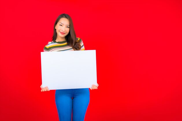 信息在红墙上用白色的空广告牌描绘美丽的亚洲年轻女子欢呼模特亚洲人