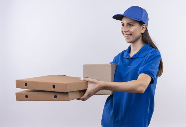 蓝色身着蓝色制服 头戴鸭舌帽的年轻送货女孩微笑着向顾客赠送比萨饼盒女孩朋友年轻人