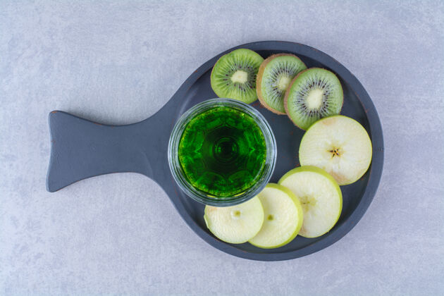 营养把一杯猕猴桃汁和苹果放在平底锅上 放在大理石桌上水果玻璃美味