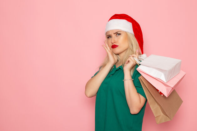 成人正面图年轻女性拿着圣诞礼物在粉红色的墙上包模型假日圣诞节新年照片的颜色风景圣诞微笑