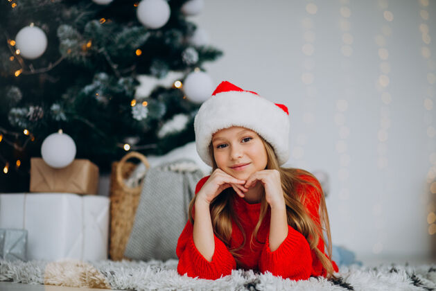乐趣圣诞树下戴圣诞帽的漂亮女孩人时尚冬天