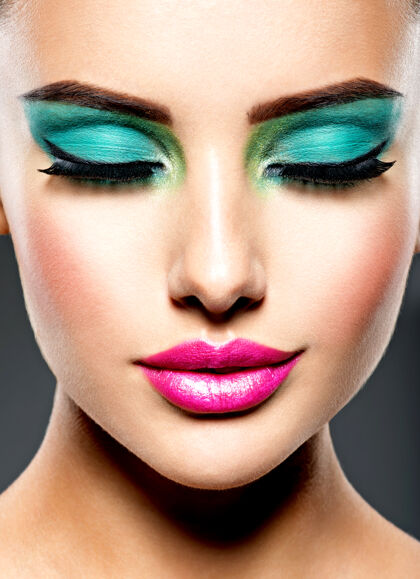 吸引一个美丽的脸上有着绿色生动眼妆的女人年轻特写化妆