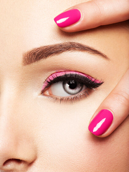 模特特写镜头：眼睛附近有粉色指甲的女人的脸粉色指甲的指甲年轻光泽女孩