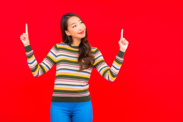 模特美丽的亚洲年轻女子在红色隔离墙上微笑中国人快乐年轻人