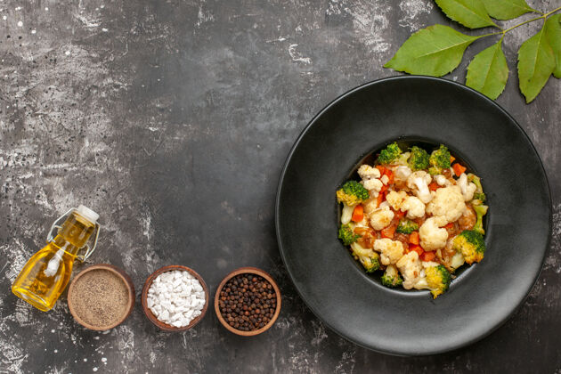 沙拉顶视图西兰花和花椰菜沙拉在黑色碗不同的香料在碗油在黑暗的表面自由空间碗炒锅平底锅