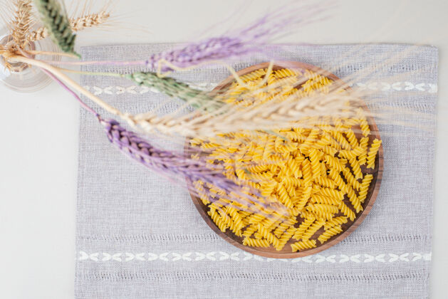 生的用五颜六色的小麦在桌布上放一盘生面食意大利面通心粉桌布