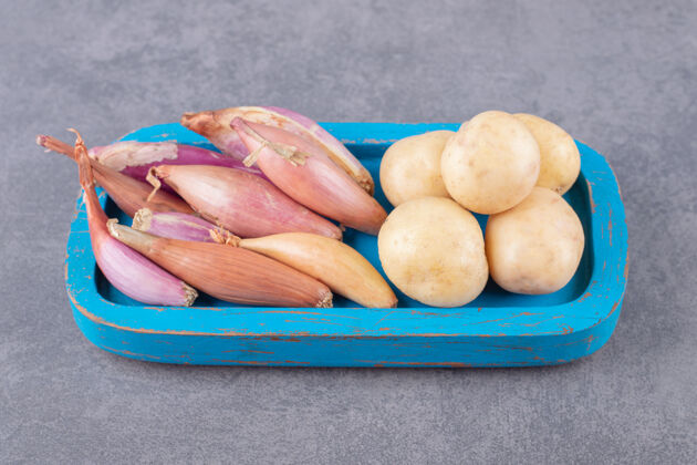 土豆生土豆和大蒜素放在蓝色的木板上新鲜自制蔬菜