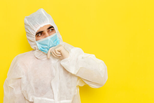 防护男科学工作者穿着白色特殊防护服 戴着无菌口罩 正对着黄色的墙壁思考思维科学科学