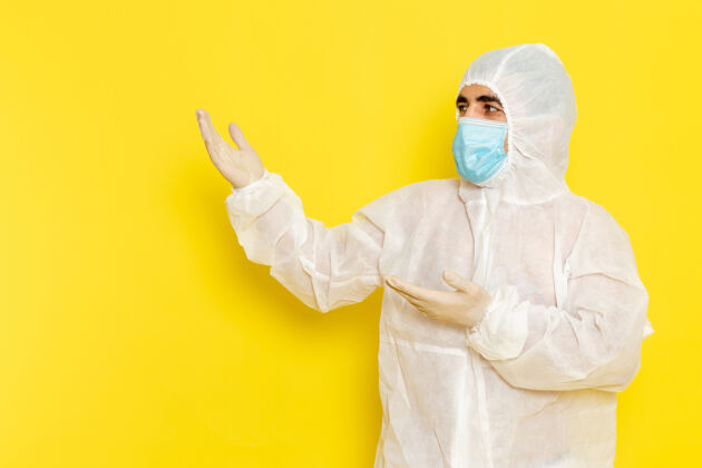 正面身穿白色防护服 带面罩 浅黄色墙壁的男性科学工作者正面图化学危险套装