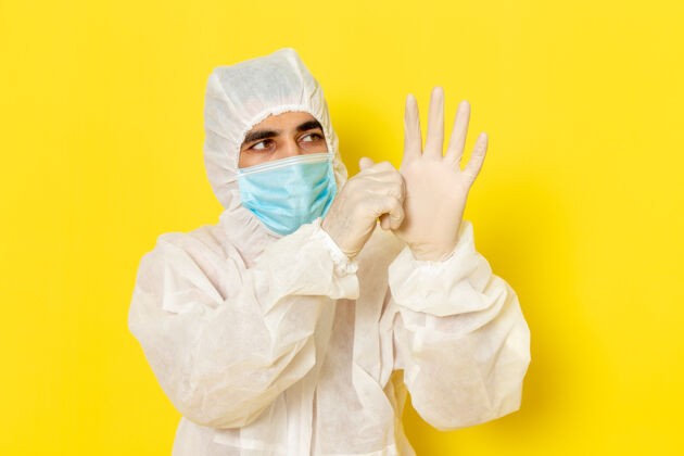 服装身穿特殊防护服 戴着面罩 戴着手套的男性科学工作者的正面图 黄色墙壁特殊制服科学