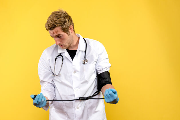 压力前视图男医生正在测量他对浅黄色背景的健康医疗病毒的压力正面医务人员听诊器