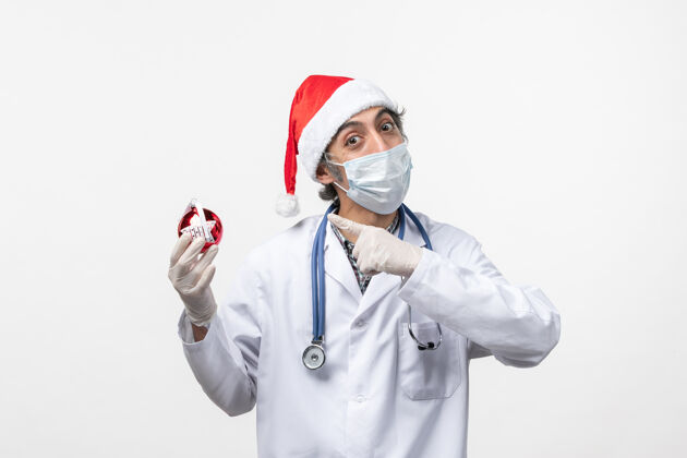 圣诞节白桌上戴着玩具面具的男医生健康可维假日病毒外套衣服护士