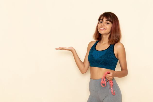 年轻身穿蓝色衬衫的年轻女性在浅白的墙壁上微笑 身体健康衬衫前面运动