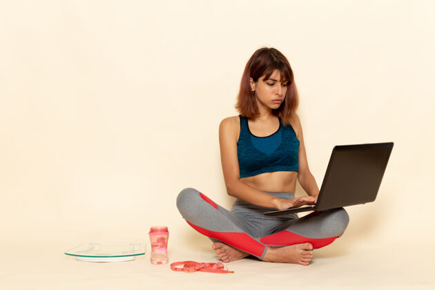 运动员年轻女性穿着蓝色衬衫 身体健康 在浅白墙上使用笔记本电脑的前视图轻漂亮成人