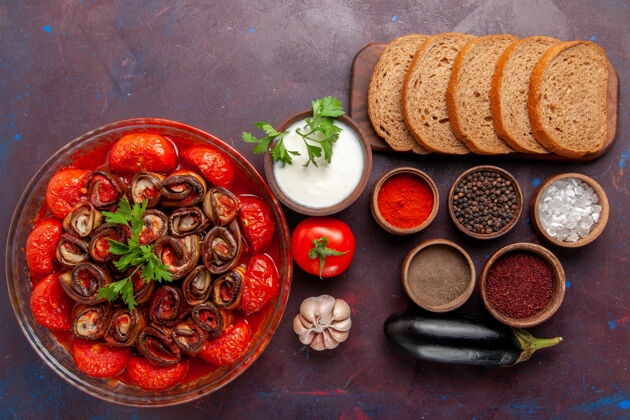 菜肴顶视图：在黑暗的桌子上放着煮熟的蔬菜 西红柿和茄子 还有调味品和面包香料桌子胡椒粉