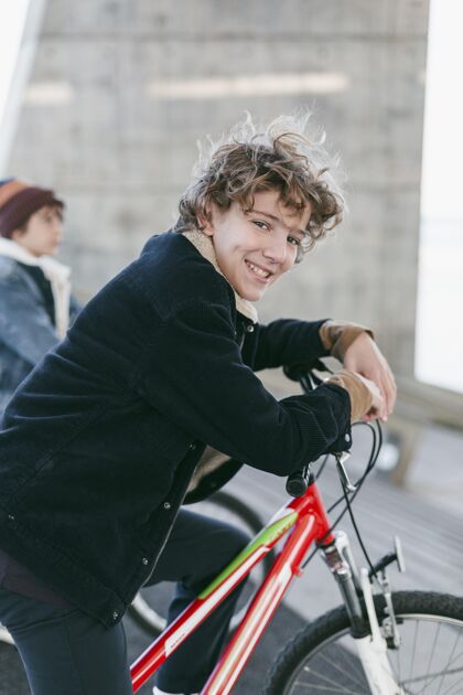 户外笑脸男孩与自行车在城市户外的侧视图放松娱乐爱好