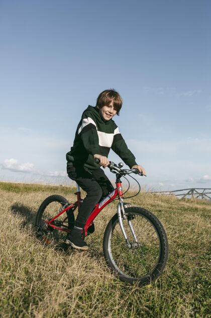 自行车男孩在户外的草地上骑自行车爱好年轻娱乐