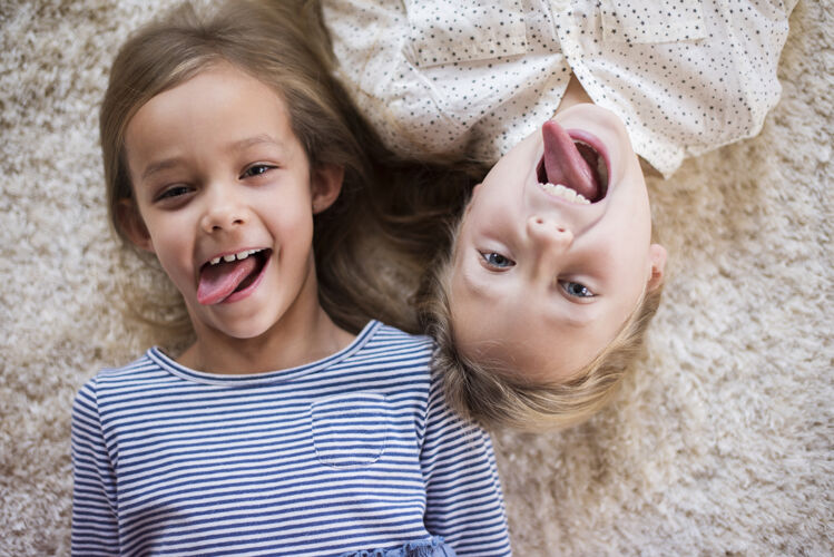 肖像两个可爱女孩滑稽的表情微笑地毯快乐