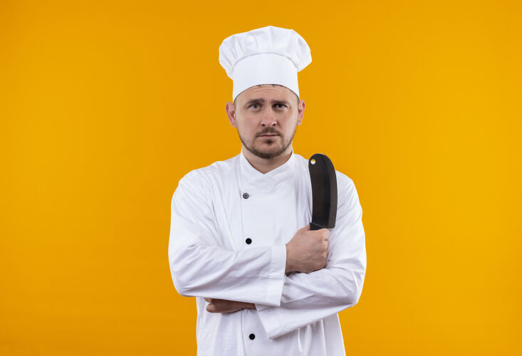 厨师年轻帅气的厨师穿着厨师制服 手里拿着菜刀 在橙色的空间里显得孤立无援橙色年轻帅气