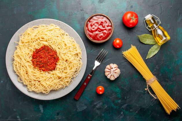 配料在深蓝色的桌子上俯瞰着意大利面和番茄肉末菜肴餐厅胡椒粉