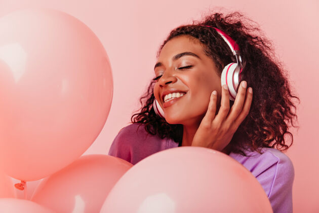欢呼戴着耳机享受派对的非洲女孩的特写照片快乐的黑人妇女在庆祝生日时听音乐乐趣时尚活动
