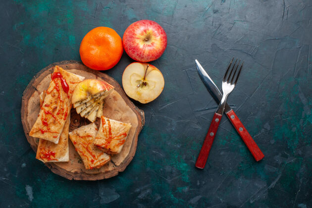 小吃在深蓝色的桌子上 俯瞰着用沙司和水果切片的生面饼酱食品可食用水果