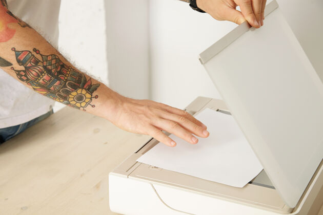 通信双手打开扫描器托盘 将纸张放在多功能电子设备内扫描文件 隔离在白色木桌上 按钮文件扫描仪