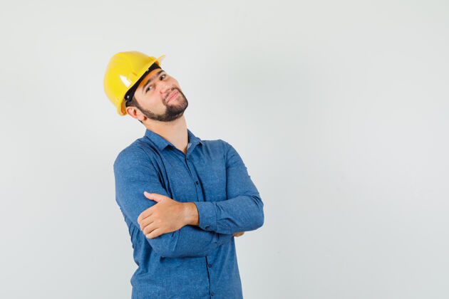 专业穿着衬衫 戴着头盔的年轻工人双手交叉站着 看上去很高兴沟通工程师工业