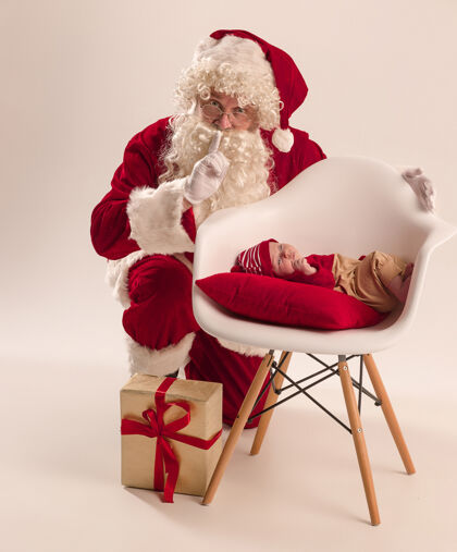 小可爱的新生小女婴的圣诞肖像 穿着圣诞服装 男人戴着圣诞老人的服装和帽子宝贝圣诞节新生儿