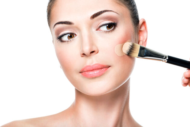 化妆品化妆师在女人脸上涂上液体色调的粉底治疗模特魅力