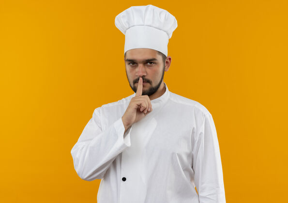 厨师身着厨师制服的年轻男厨师在橙色的空间里默不作声年轻手势沉默