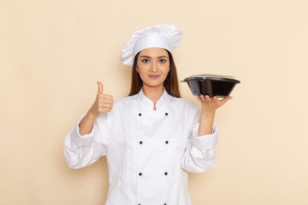 食物身穿白色厨师服的年轻女厨师正对着白色墙壁微笑着拿着平底锅厨师护士制服