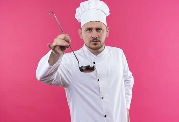 制服年轻帅气的厨师穿着厨师制服 伸出勺子 看上去孤立地站在粉红色的空间里厨师年轻长相