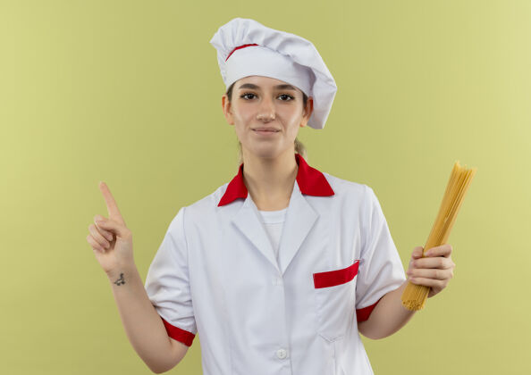制服穿着厨师制服的年轻漂亮厨师手拿意大利面 在绿地上竖起手指厨师年轻厨师