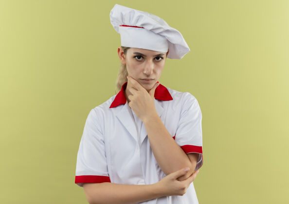 手体贴的年轻漂亮厨师 身着厨师制服 手放在下巴上 在绿地上显得孤立无援漂亮放制服