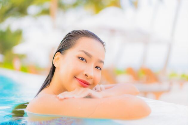 蓝色肖像美丽的亚洲年轻女子放松休闲周围的室外游泳池与海洋海滩年轻人娱乐夏威夷
