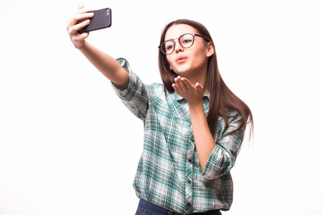 女人自拍..迷人的年轻女子手持手机 站在白色的背景下拍照电话聪明年轻